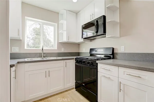 a kitchen with white cabinets and a window
