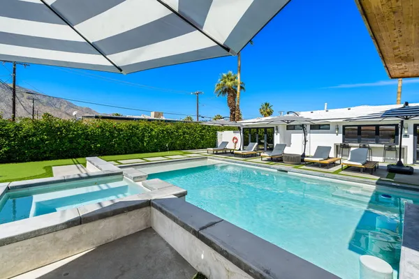 a view of swimming pool with a table and chairs under an umbrella