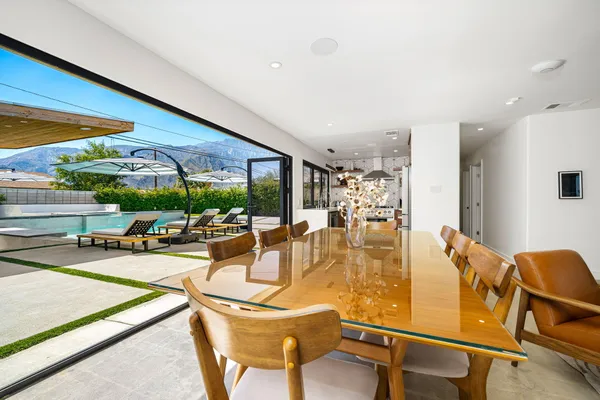 a dining room with furniture a large window and palm tree