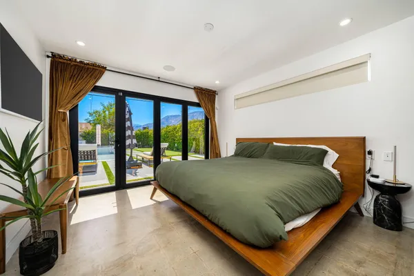 a bed sitting in a bedroom next to a large window with potted plants