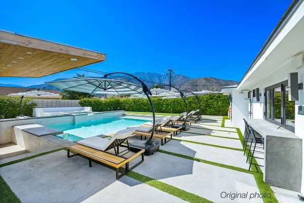 a view of a backyard with lawn chairs under an umbrella