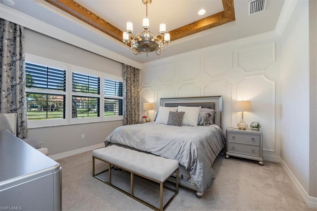 13422 Silktail Drive Naples, FL 34109 - Photo 13 of 37 Bedroom featuring an inviting chandelier, a tray ceiling, visible vents, and carpet floors