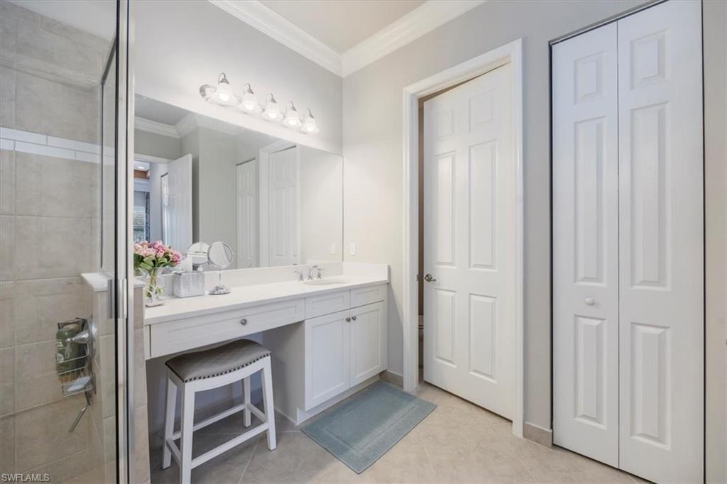 13422 Silktail Drive Naples, FL 34109 - Photo 16 of 37 Bathroom with tile patterned flooring, ornamental molding, a tile shower, a closet, and vanity
