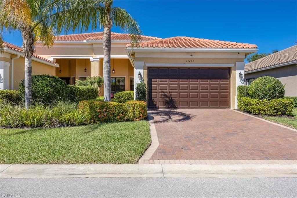 13422 Silktail Drive Naples, FL 34109 - Photo 2 of 37 Mediterranean / spanish-style home featuring a front lawn, a tile roof, stucco siding, decorative driveway, and an attached garage