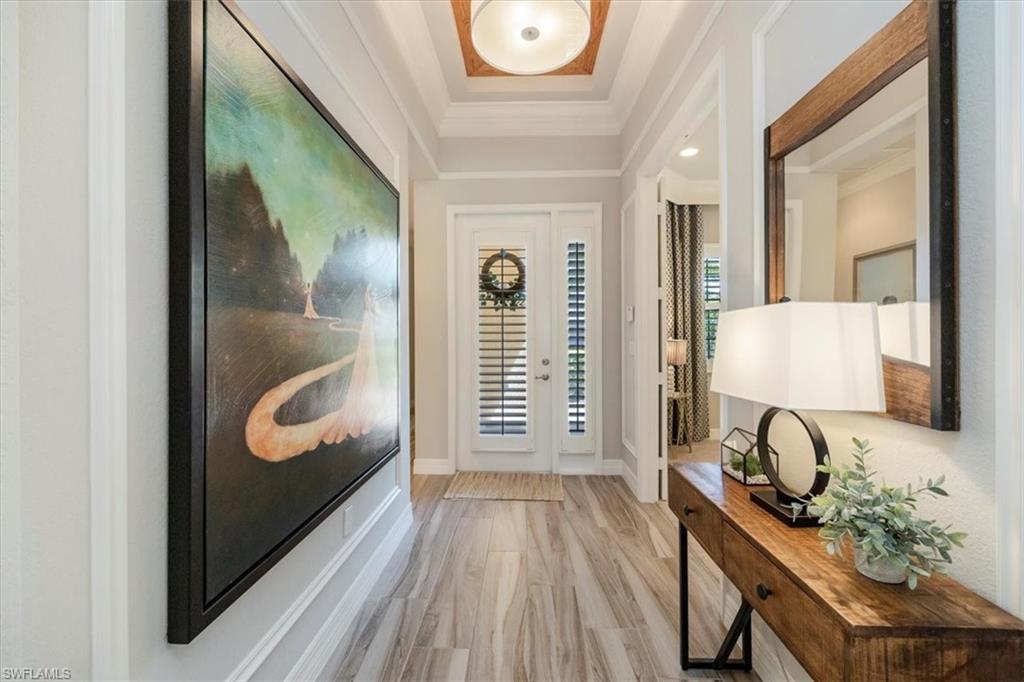 13422 Silktail Drive Naples, FL 34109 - Photo 5 of 37 Entrance foyer featuring crown molding, a tray ceiling, baseboards, and light wood finished floors