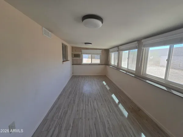 a view of empty room with wooden floor and fan