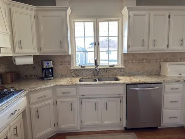 a kitchen with white cabinets and sink