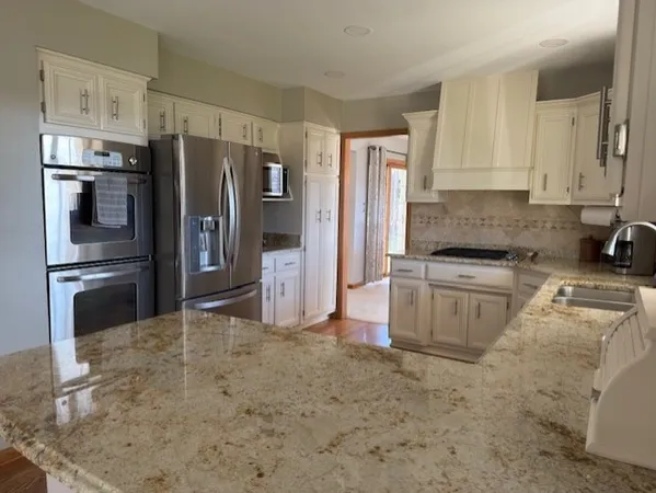a kitchen with granite countertop a refrigerator sink and stainless steel appliances