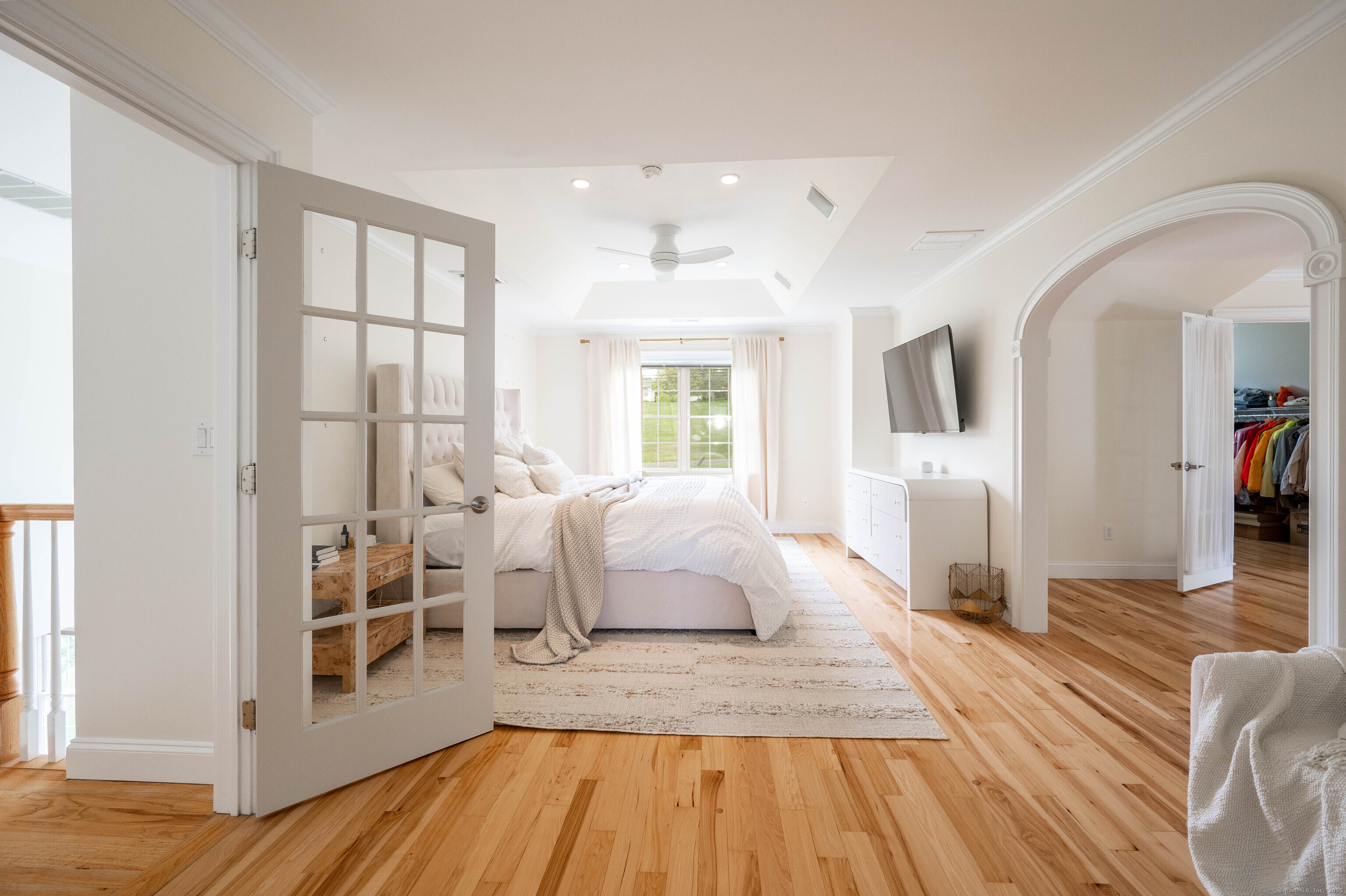 557 Upper Grassy Hill Road Woodbury, CT 06798 - Photo 17 of 40 a spacious bedroom with a balcony a bed and wooden floor