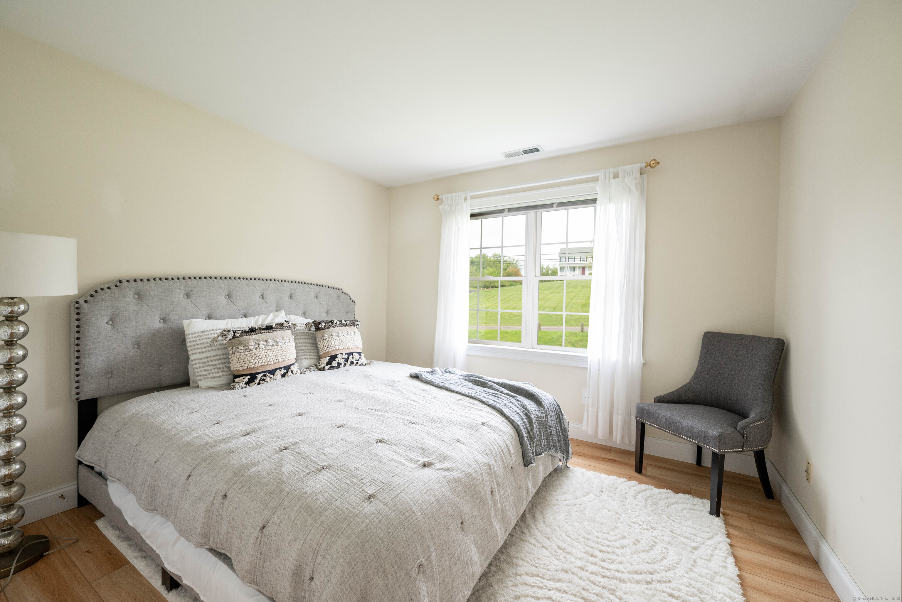 557 Upper Grassy Hill Road Woodbury, CT 06798 - Photo 23 of 40 a large bed sitting in a bedroom next to a window with a chair