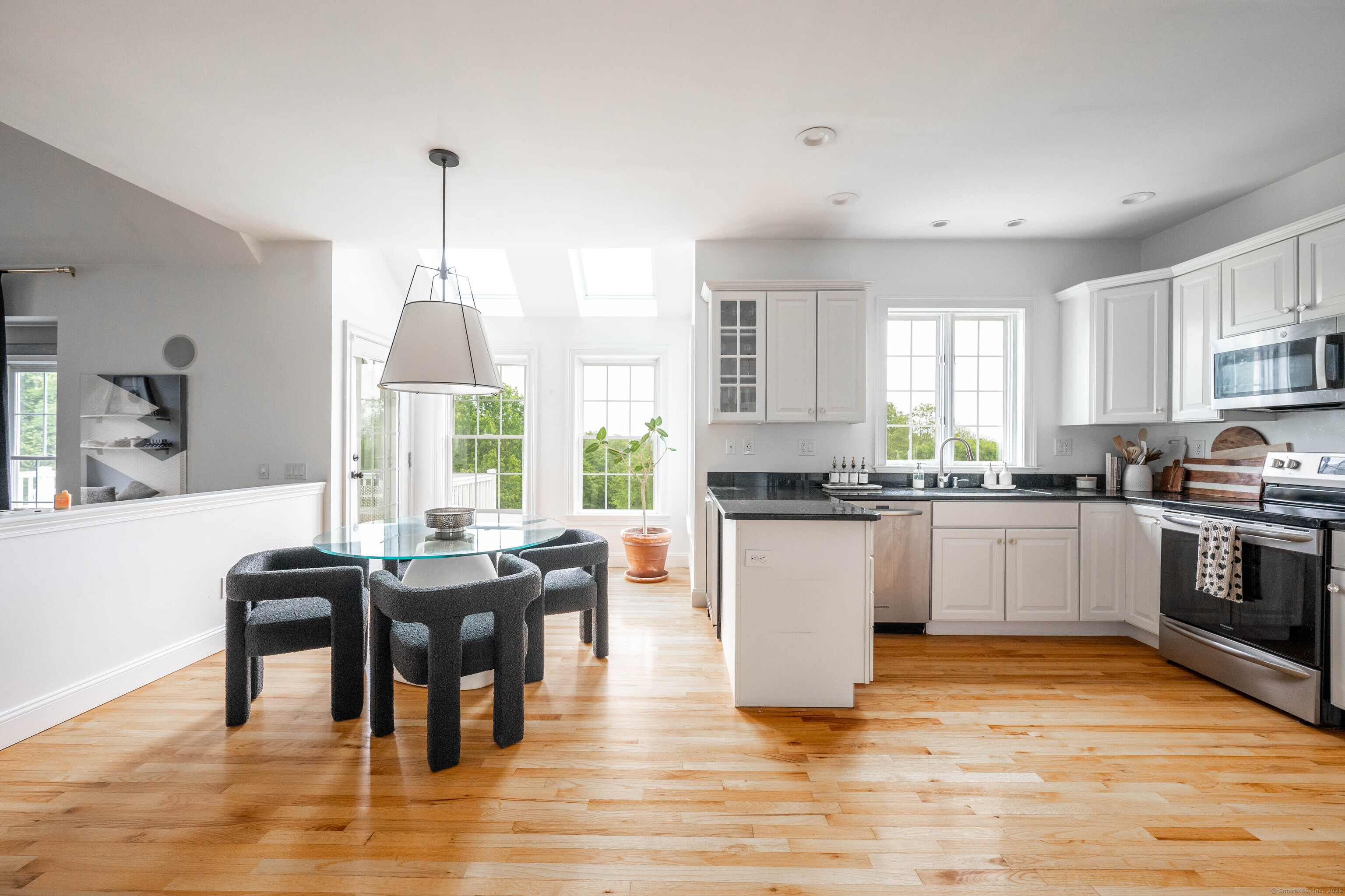 557 Upper Grassy Hill Road Woodbury, CT 06798 - Photo 10 of 40 a kitchen with stainless steel appliances granite countertop a stove top oven a sink dishwasher a dining table and chairs with wooden floor