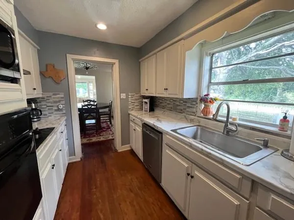 a kitchen with a sink a counter top space appliances and cabinets