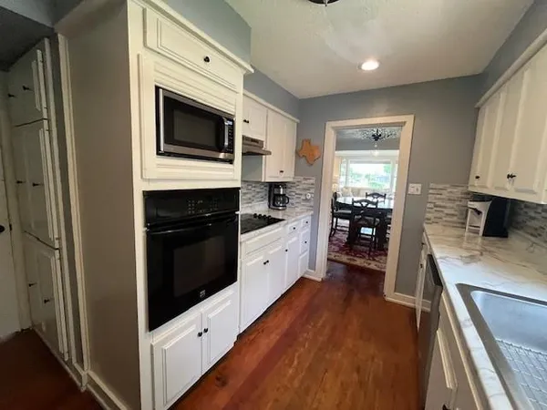 a kitchen with stainless steel appliances white cabinets and wooden floor