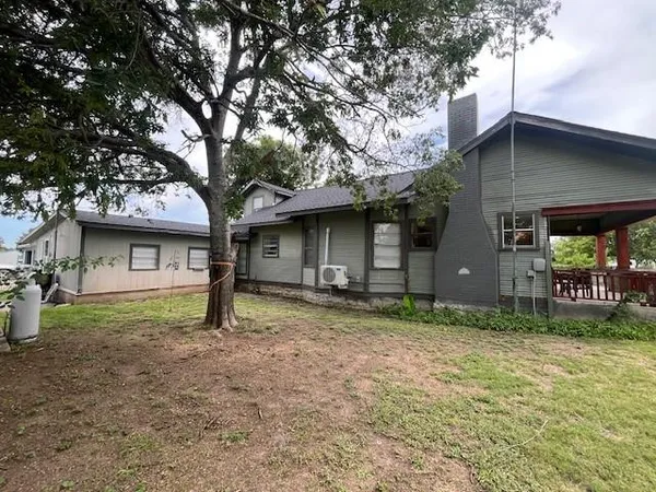a view of a house with a yard and large tree