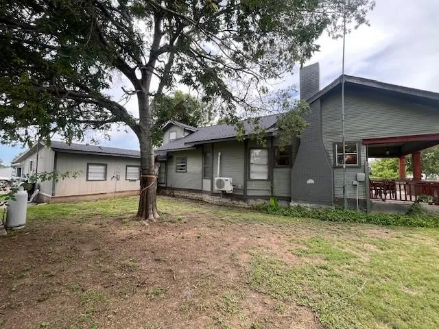 a view of a house with a yard and large tree
