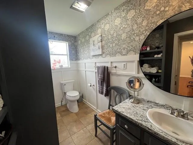 a bathroom with a granite countertop toilet sink and mirror