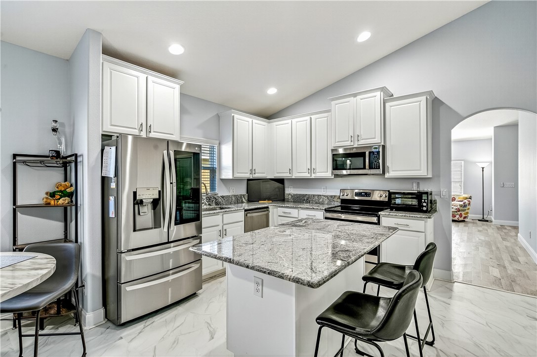 535 Valencia Circle Southwest Vero Beach, FL 32968 - Photo 1 of 36 a kitchen with stainless steel appliances granite countertop a refrigerator a stove a sink a dining table and chairs with wooden floor