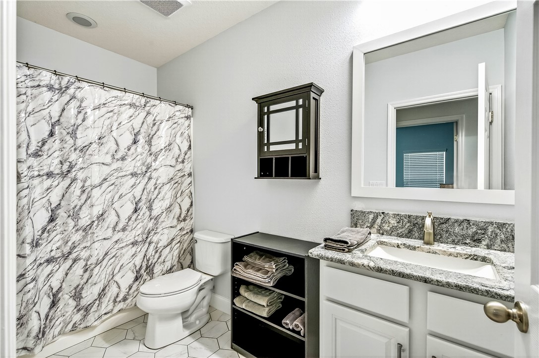 535 Valencia Circle Southwest Vero Beach, FL 32968 - Photo 23 of 36 a bathroom with a granite countertop toilet sink and mirror