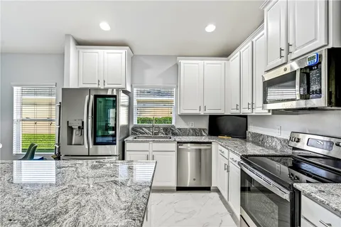 a kitchen with stainless steel appliances granite countertop a stove a sink and a microwave