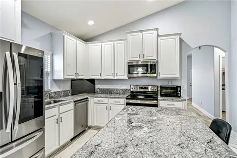 a kitchen with stainless steel appliances granite countertop a refrigerator stove top oven and sink