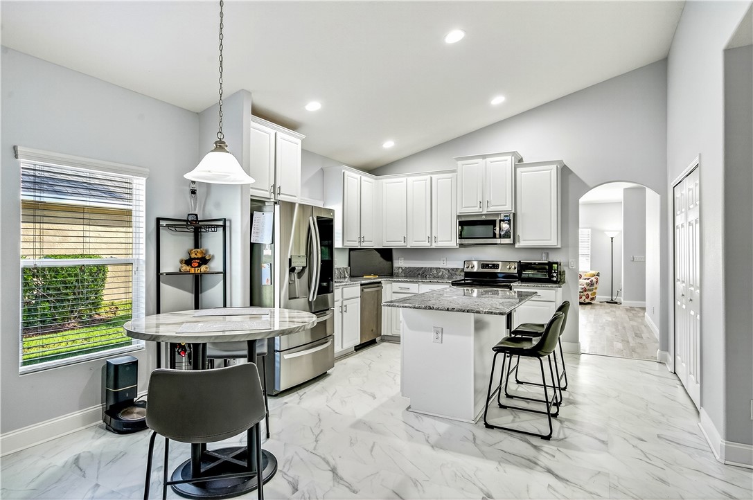 535 Valencia Circle Southwest Vero Beach, FL 32968 - Photo 10 of 36 a kitchen with stainless steel appliances kitchen island granite countertop a refrigerator a stove a sink a dining table and chairs with wooden floor
