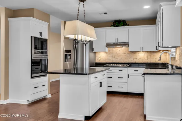 a kitchen with stainless steel appliances a stove a refrigerator and white cabinets