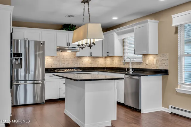 a kitchen with stainless steel appliances granite countertop a sink a stove a refrigerator a center island and a window