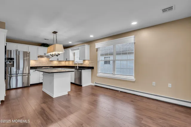 a kitchen with stainless steel appliances kitchen island a hardwood floor and a sink