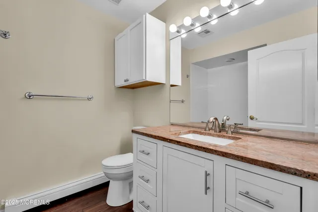 a bathroom with a granite countertop sink a toilet and a mirror