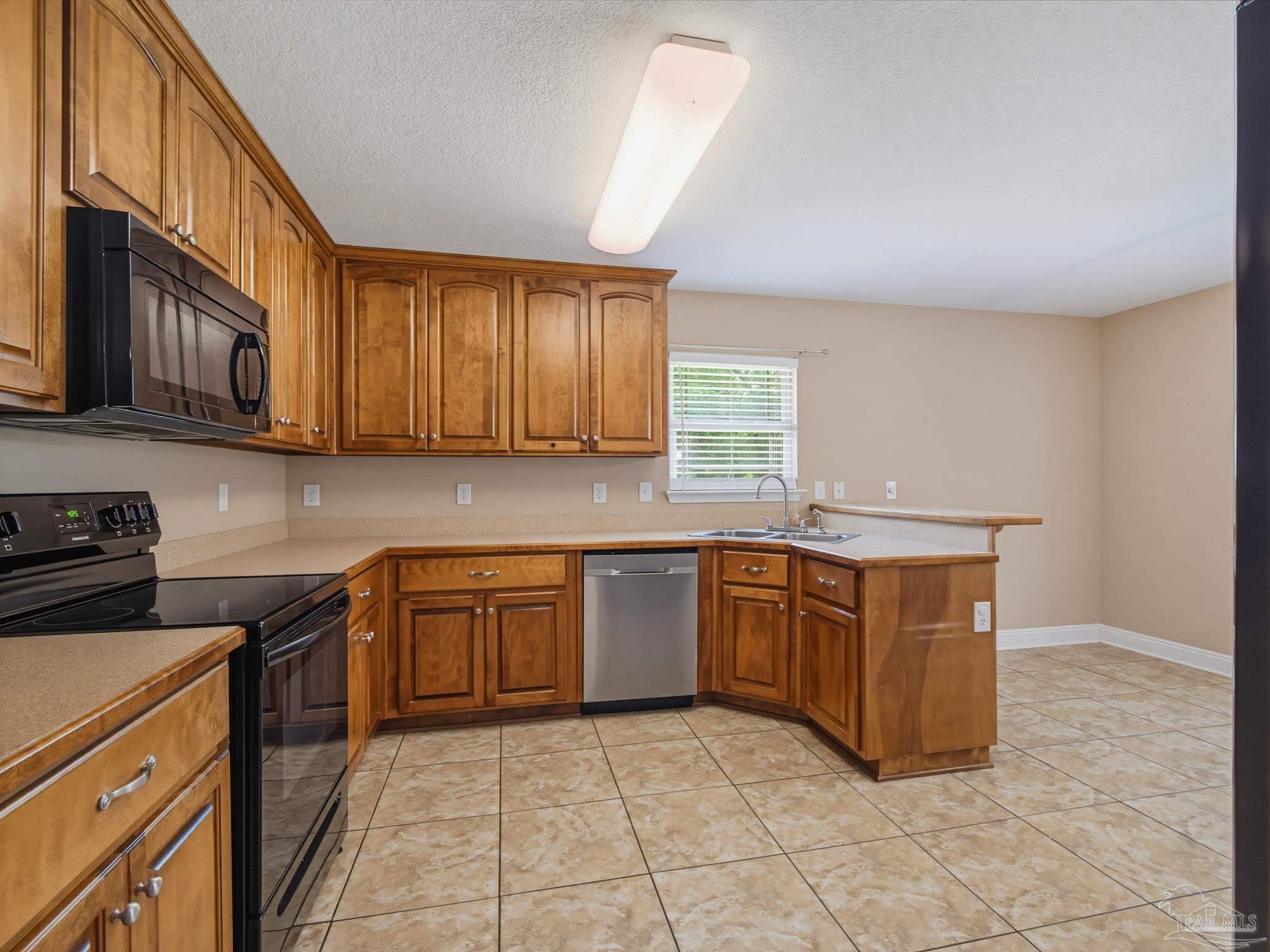 5567 Jones Street Milton, FL 32570 - Photo 20 of 48 a kitchen with stainless steel appliances granite countertop a stove a sink and a microwave