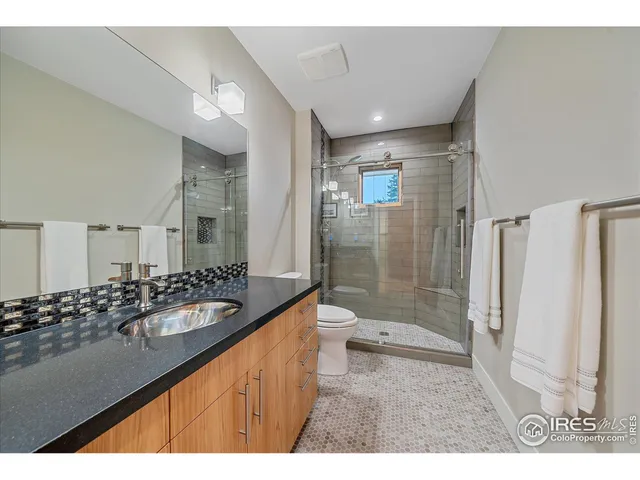 a bathroom with a sink a toilet a mirror and shower