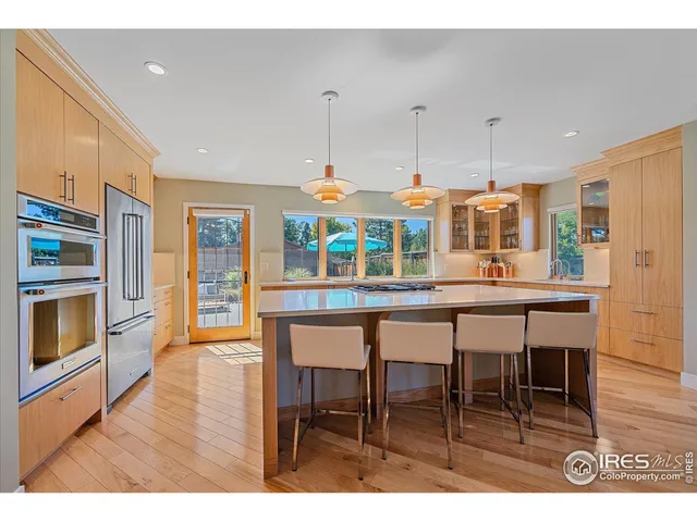 a kitchen with stainless steel appliances kitchen island granite countertop a table chairs and a refrigerator