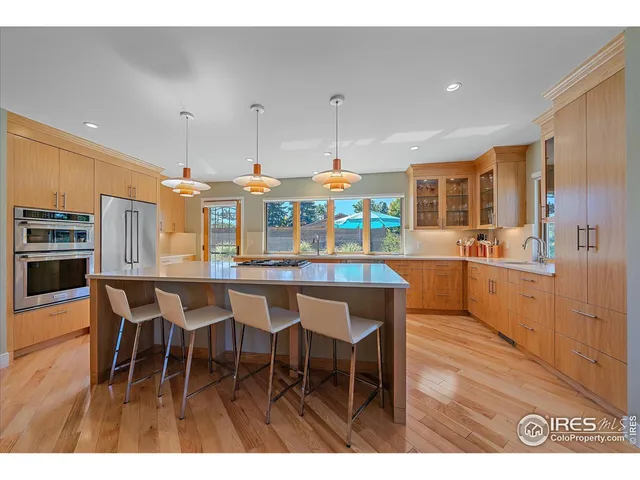 a kitchen with stainless steel appliances kitchen island granite countertop a table chairs sink and cabinets