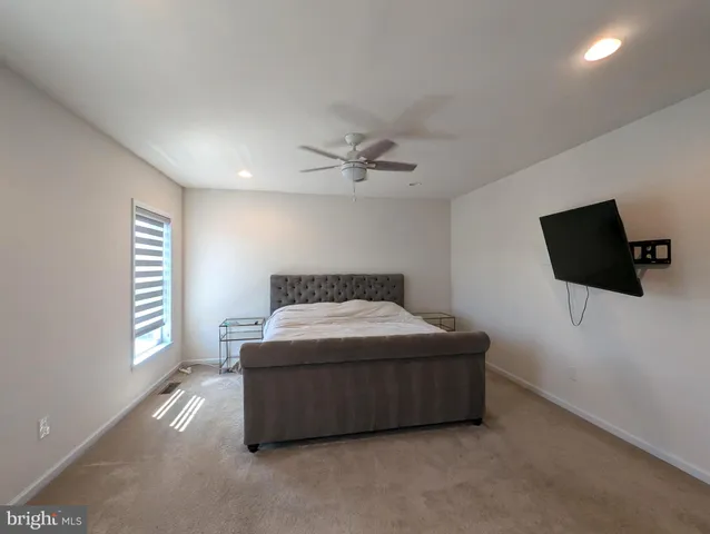 a living room with a bed a flat screen tv and a window