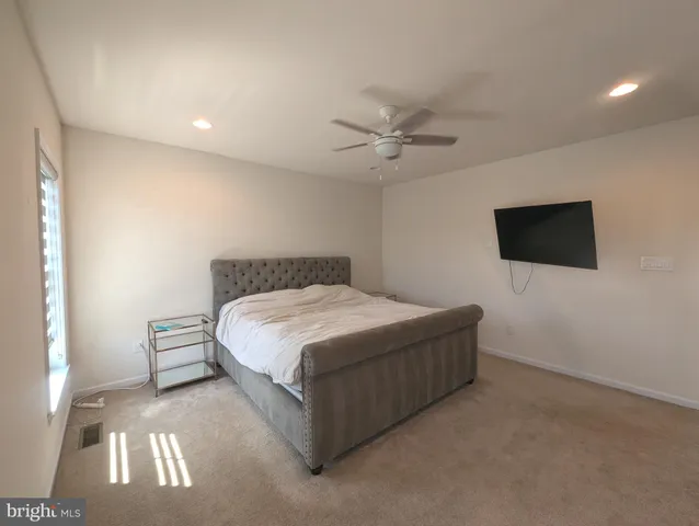a spacious bedroom with a bed and a flat screen tv