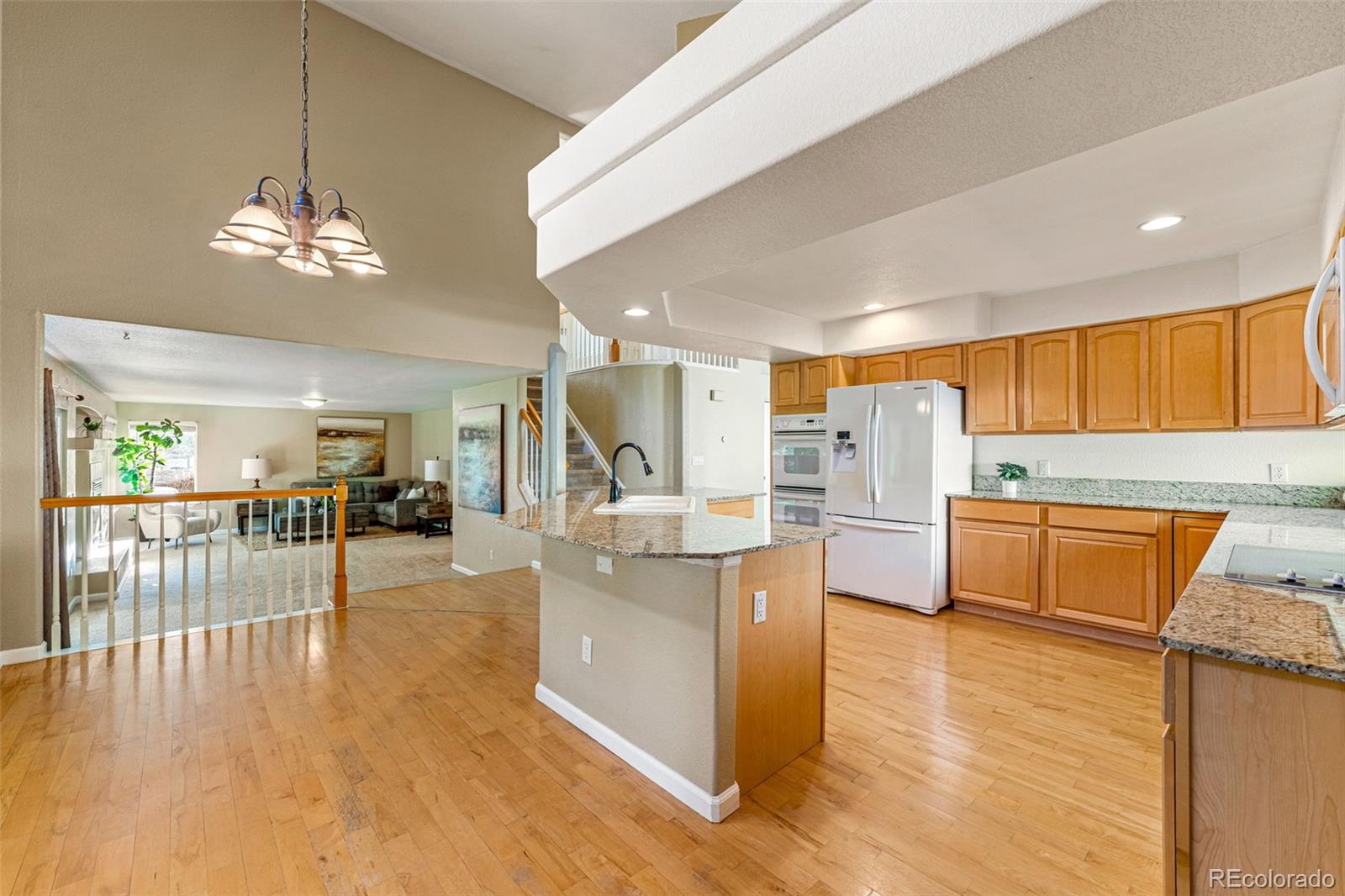 276 East Fair Lane Centennial, CO 80121 - Photo 11 of 38 a view of a kitchen with kitchen island a large counter top space stainless steel appliances a chandelier and living room view