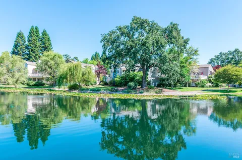 a view of a lake with a yard and large trees