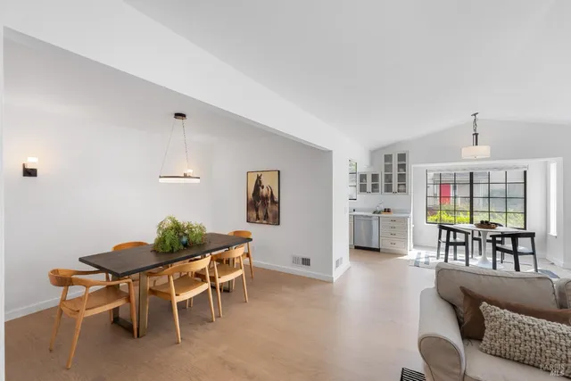 a living room with furniture and a dining table with wooden floor
