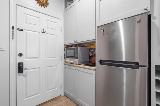a view of a refrigerator in kitchen and white cabinets