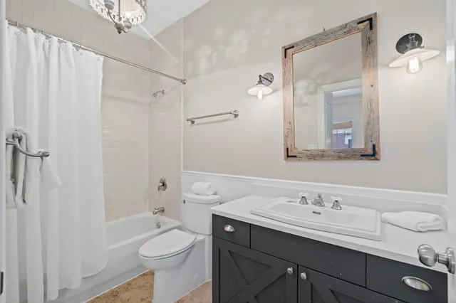 a bathroom with a toilet a sink a mirror a bathtub and vanity