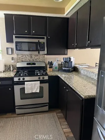 a kitchen with stainless steel appliances granite countertop a stove a sink and a microwave