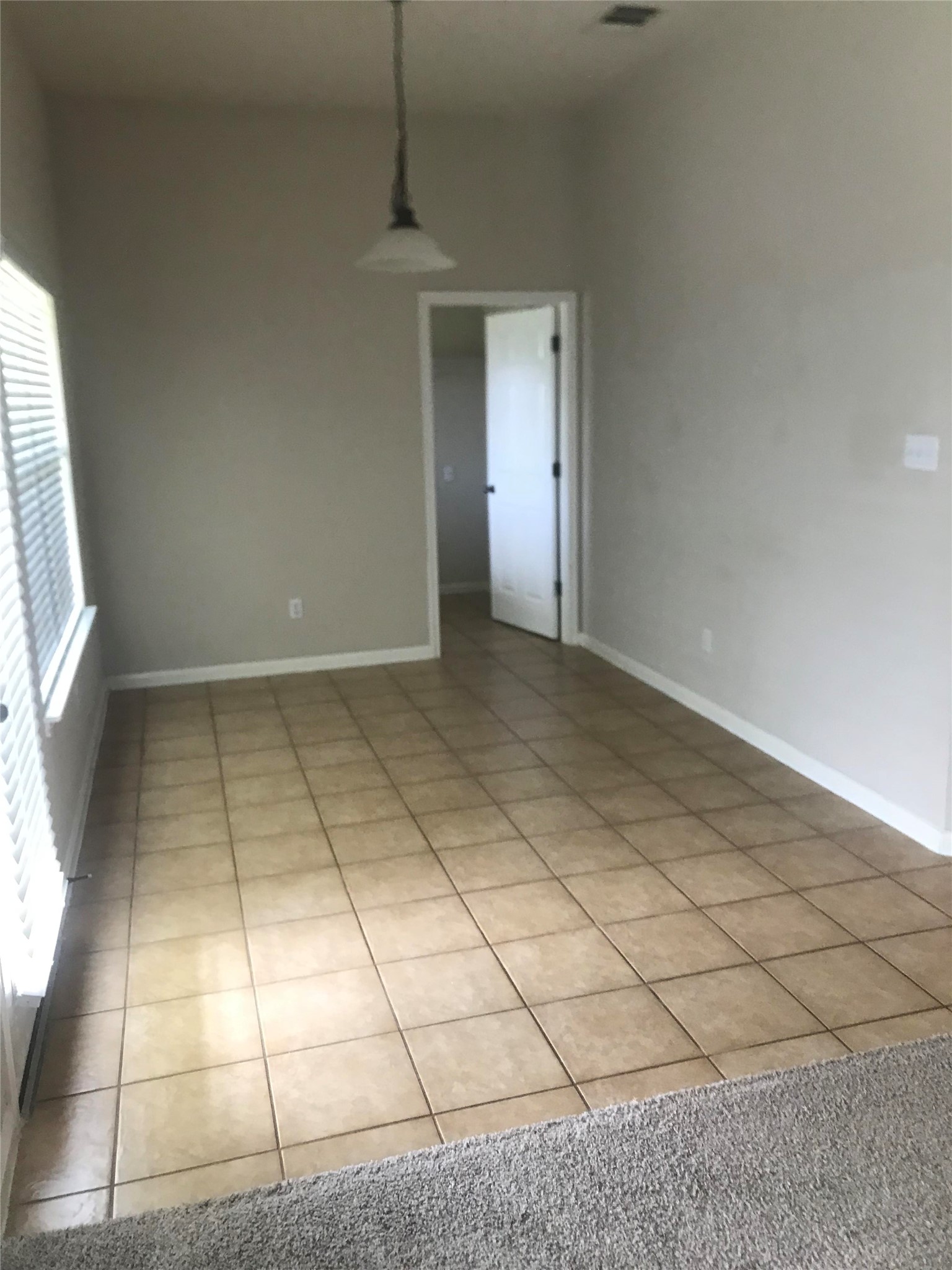 913 Rochester Castle Way Pflugerville, TX 78660 - Photo 7 of 25 Clean tile flooring extends into an adjacent carpeted area, offering flexible living space.