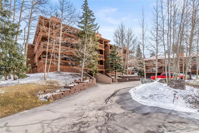 a view of white apartments with large trees