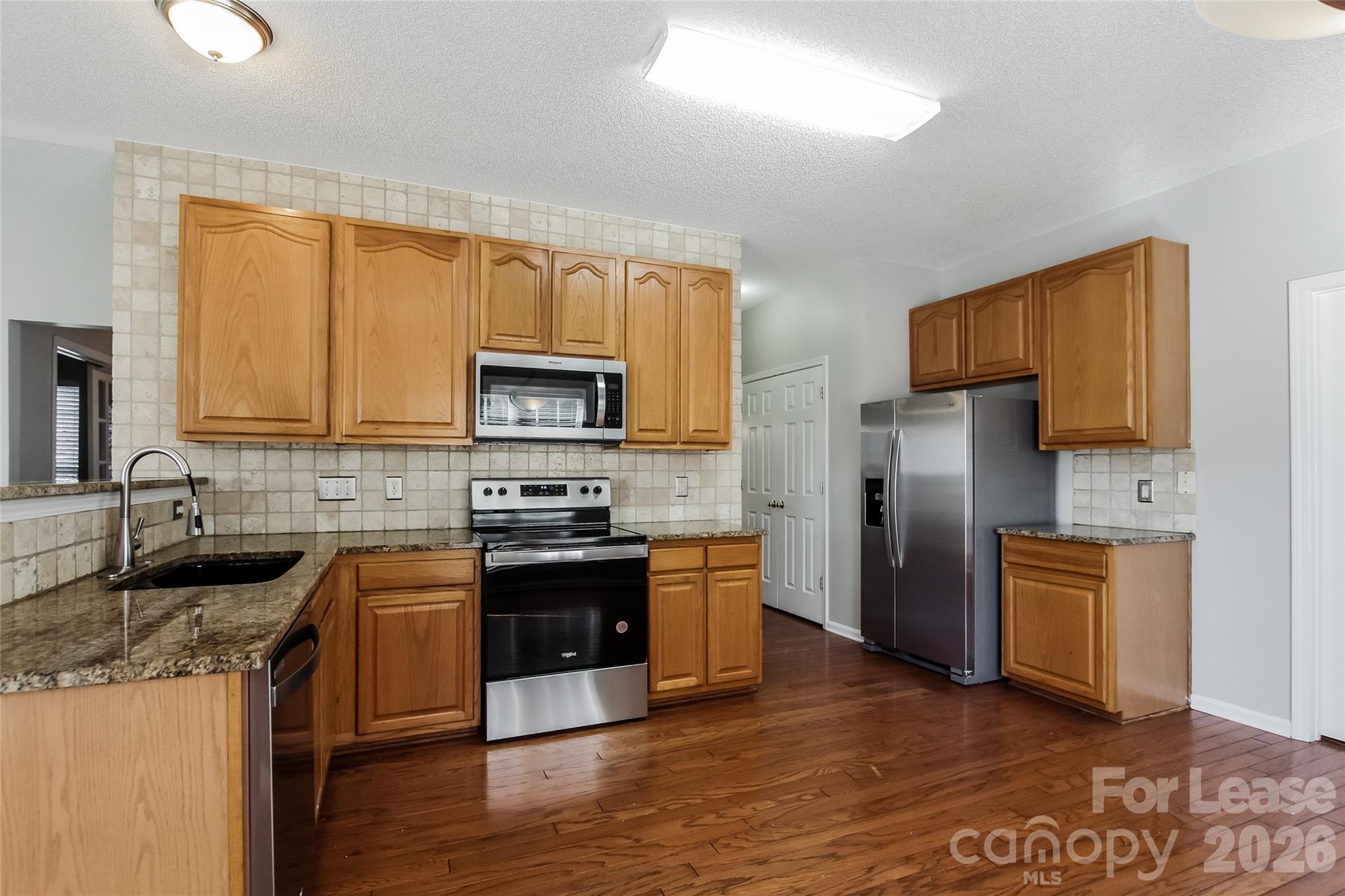 10802 Gold Pan Road Charlotte, NC 28215 - Photo 3 of 15 a kitchen with granite countertop a refrigerator stove top oven and sink