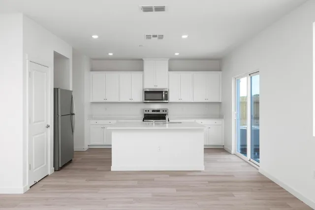 a large kitchen with stainless steel appliances a refrigerator and a stove top oven