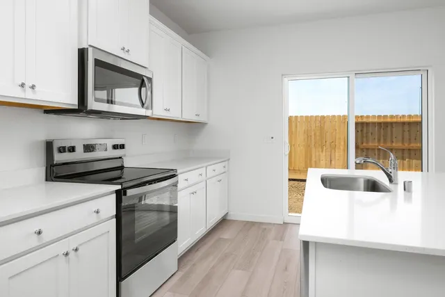 a kitchen with stainless steel appliances granite countertop a stove a sink and a microwave