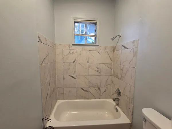 a brick house that has a small yard and a large tree