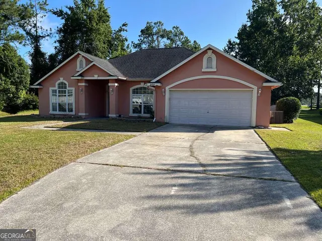 a front view of house with yard and trees in the background