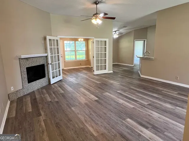 a view of an empty room with wooden floor fireplace and a window