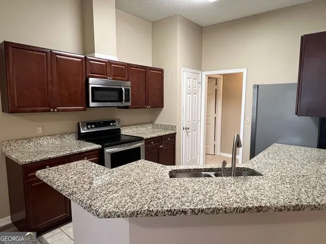 a kitchen with kitchen island granite countertop a sink stove and refrigerator